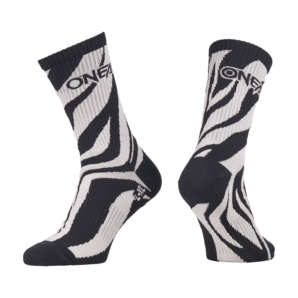 L'O'NEAL MTB Performance Sock WILD è un paio di calzini bianchi e neri con un accattivante design a strisce zebrate e la scritta "O'NEAL" nella parte superiore. Un calzino è mostrato dal davanti, l'altro di lato.