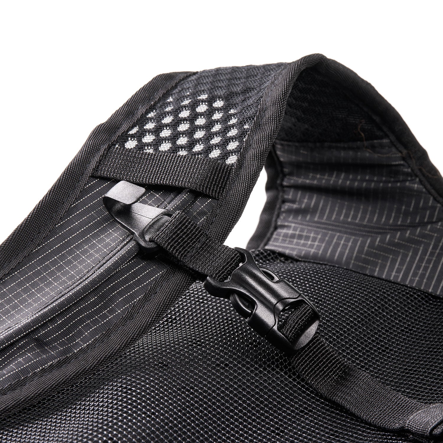 Nahaufnahme eines schwarzen Mesh-Rucksackriemens mit einer Kunststoffschnalle und einem Bereich mit weißen reflektierenden Punkten zur besseren Sichtbarkeit. Der Stoff weist Nahtlinien und subtile Texturdetails auf.