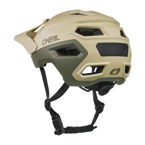 Sobre fondo blanco se muestra un casco O'NEAL Trailfinder EVO Solid de color marrón claro y verde oliva con visera, orificios de ventilación, mentonera negra ajustable y rueda de ajuste trasera.