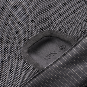Nahaufnahme des schwarzen Mesh-Gewebes des O'NEAL Europe JUNCTION MTB Protektorrucksacks, die einen rechteckigen Ausschnitt mit einem weichen, dunklen Innenaufnäher mit dezentem Text und Symbolen zeigt; unten rechts erscheint der Nadelstreifenstoff.