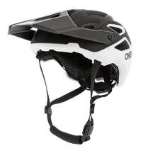 Der O'NEAL PIKE Helm SOLID von O'NEAL ist ein schwarz-weißer Fahrradhelm mit Visier, verstellbaren Riemen und mehreren Belüftungsöffnungen, dargestellt in Seitenansicht auf weißem Hintergrund.