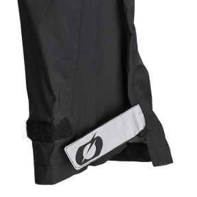 Nahaufnahme einer schwarzen O'NEAL TORRENT Regenhose mit Klettverschluss und reflektierendem Blitz-Patch, ideal als atmungsaktive Regenhose für den Radsport, abgebildet auf weiß.