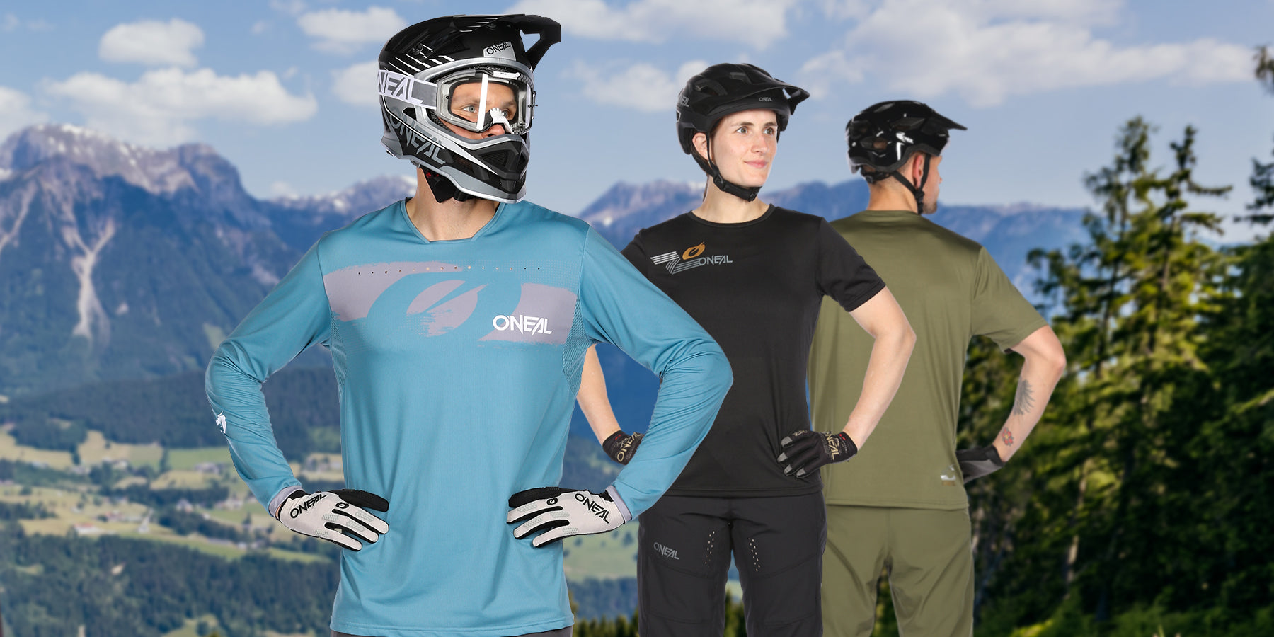 Drei Personen in Mountainbike-Ausrüstung stehen vor einer malerischen Bergkulisse. Die Person links trägt ein blaues Langarmtrikot und einen Integralhelm, die Person in der Mitte trägt ein schwarzes T-Shirt und einen schwarzen Helm und die Person rechts trägt Grün.