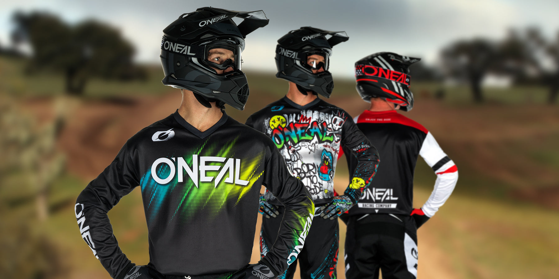 Drei Motocrossfahrer in farbenfroher O'Neal-Ausrüstung und Helmen stehen im Freien. Jeder Fahrer blickt in eine andere Richtung und zeigt verschiedene Designs seiner Outfits vor einem unscharfen natürlichen Hintergrund.