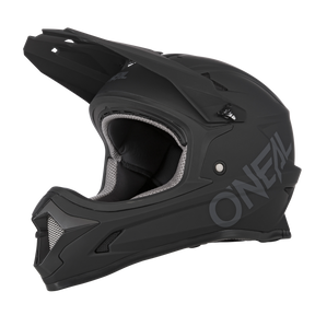 Le casque O'NEAL SONUS SOLID est un casque VTT fullface noir mat avec visière et protège-menton, avec une grande marque O'NEAL sur le côté et un rembourrage intérieur gris et noir.