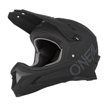 Le casque O'NEAL SONUS SOLID est un casque VTT fullface noir mat avec visière et protège-menton, avec une grande marque O'NEAL sur le côté et un rembourrage intérieur gris et noir.