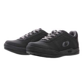 Un paio di scarpe O'NEAL Pinned SPD in nero con lacci e suola grigio scuro, con un sottile logo laterale e un design low-top, del marchio O'NEAL, mostrate una accanto all'altra su uno sfondo a tinta unita.