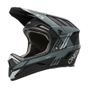 Der O'NEAL BACKFLIP Helm STRIKE ist ein mattschwarzer und grauer Integralhelm mit kantigen Belüftungsöffnungen, einem Visier und fortschrittlicher Renntechnik. Die durch die Öffnung sichtbare Polsterung macht ihn ideal für Motocross- und Mountainbike-Fahrer, die Spitzenleistung suchen.