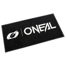 La alfombra O'NEAL es una alfombra rectangular negra con las letras "O'NEAL" y un logotipo "O" estilizado en letras blancas y llamativas en el centro.