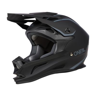 Il casco O'NEAL Drop DH Solid è un casco integrale nero opaco con accenti grigio-blu. Ha una visiera quadrata e una mentoniera con il marchio "O'Neal" in bianco sul lato. Questo casco aerodinamico è stato progettato per il ciclismo fuoristrada e offre sicurezza e comfort.
