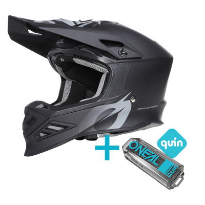 Un casco integrale in nero e grigio con visiera e grafica stilizzata, accompagnato da una scatola con la scritta "O'NEAL F-SRS Solid Quin Bundle" sotto il piccolo logo blu "O'NEAL Europe".