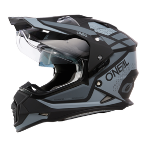 El casco Sierra R de O'NEAL se muestra de perfil en negro y gris y se caracteriza por una visera transparente, diseño aerodinámico y aberturas de ventilación sobre fondo negro.