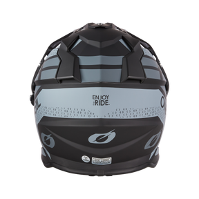 El Casco O'NEAL Sierra R, en negro mate por detrás con motivos geométricos en gris claro y "ENJOY THE RIDE." impreso en el centro, es perfecto para cualquier aficionado a los cascos de moto.