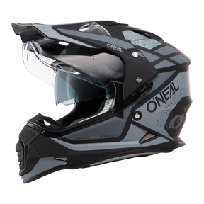 El casco Sierra R de O'NEAL en negro y gris con visera transparente, diseño angular y aberturas de ventilación detalladas se muestra de perfil sobre fondo blanco.