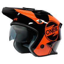 El casco O'NEAL VOLT CORP de O'NEAL es un casco de moto negro y naranja con visera transparente, forma aerodinámica, acolchado interior, gráficos llamativos y el lema "Enjoy the ride" junto al logotipo de O'NEAL.