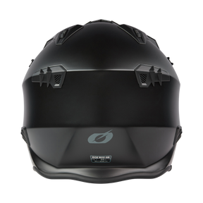 A matt black O'NEAL VOLT helmet SOLID motorcycle helmet seen from behind, with angular ventilation openings, geometric patterns, a discreet O'NEAL logo and a certification sticker near the base.