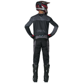 A person in black and gray motocross gear stands with his hands on his hips, wearing an O'NEAL jersey, tall black boots and O'NEAL ELEMENT Pants RACEWEAR.