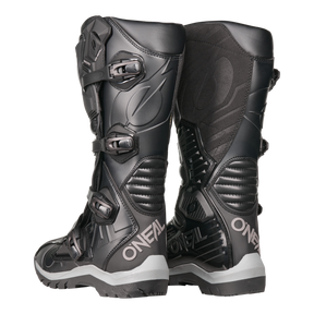 La bota O'NEAL RMX Adventure en negro con hebillas y detalles texturizados sobre fondo blanco es el complemento ideal para cualquier colección de deportes de motor.