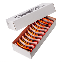 Eine weiße O'NEAL-Schachtel mit der Aufschrift "O'NEAL B-ZERO Goggle 10pcs" enthält 10 orangefarbene und schwarze O'NEAL B-ZERO-Schutzbrillen, jede ordentlich in ihrem eigenen Fach mit teilweise geöffnetem Deckel angeordnet.