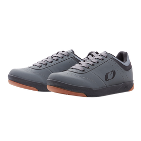 Une paire de POMPES grises O'NEAL FLAT avec semelle en caoutchouc et lacets, logo latéral discret, illustré sur fond blanc - idéal comme chaussure de vélo plate et un excellent ajout à ta collection d'accessoires de vélo.