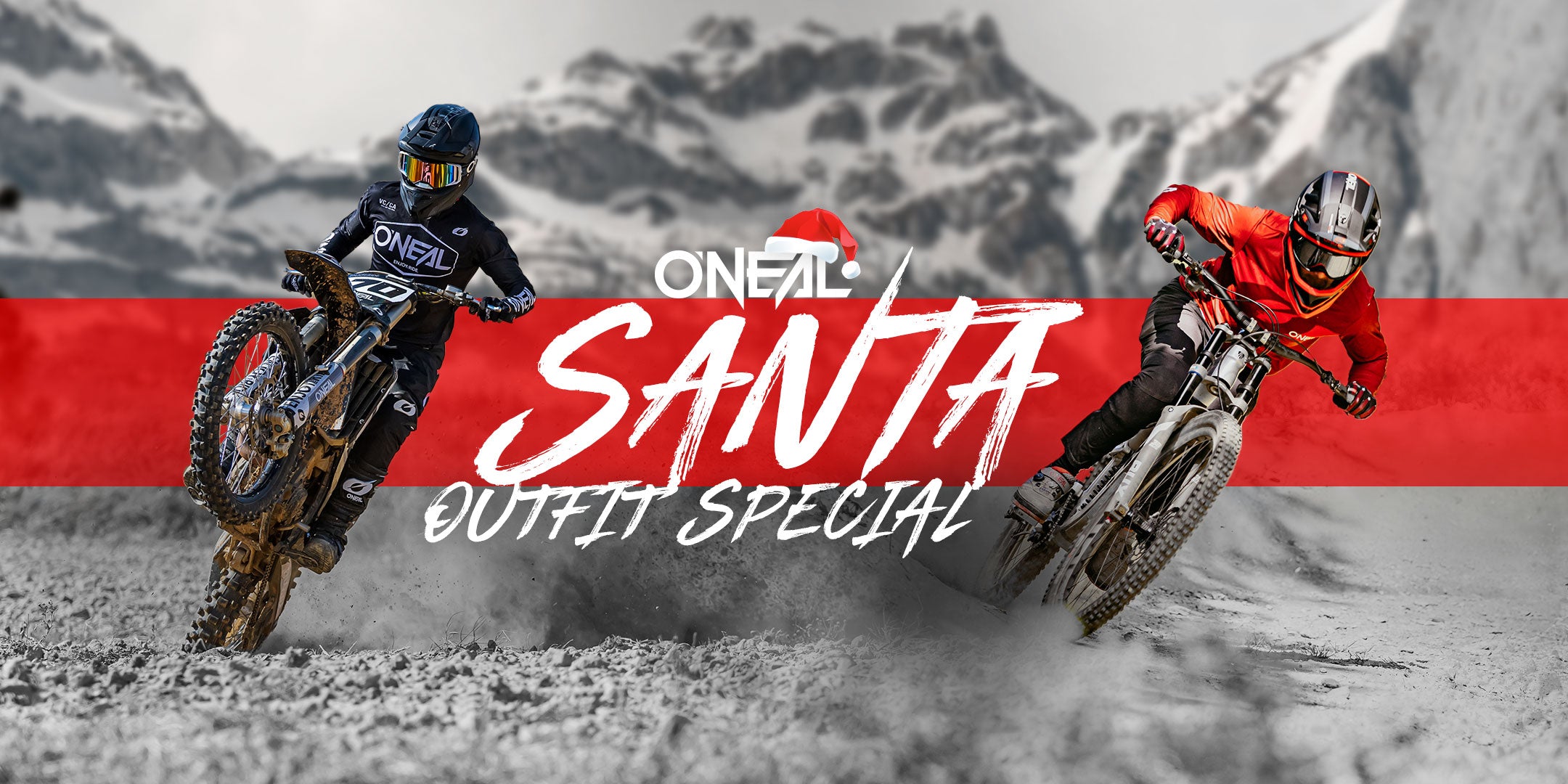 Zwei Mountainbiker in Motorradmontur fahren auf einem Feldweg mit schneebedeckten Bergen im Hintergrund. Der Text lautet „O'NEAL Santa Outfit Special“ mit einem roten Streifen und einer Weihnachtsmannmützengrafik.